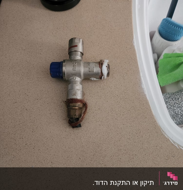 שסתום מתכת עם חיבורים על משטח עבודה